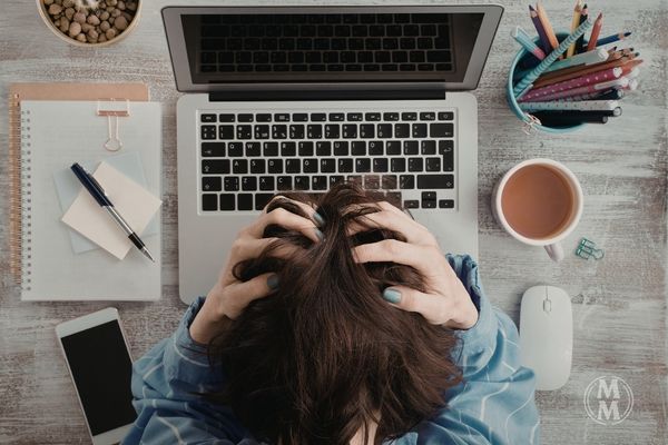 midlife woman overwhelmed with brain fog holding head at laptop feeling mentally fatigued