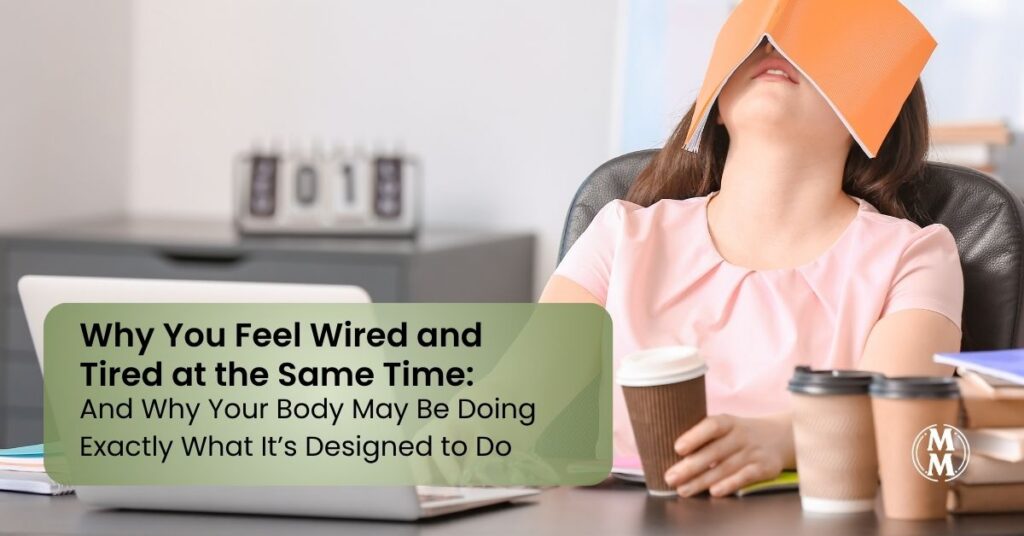 woman at desk wired and tired with a book on her head and several coffee cups around her